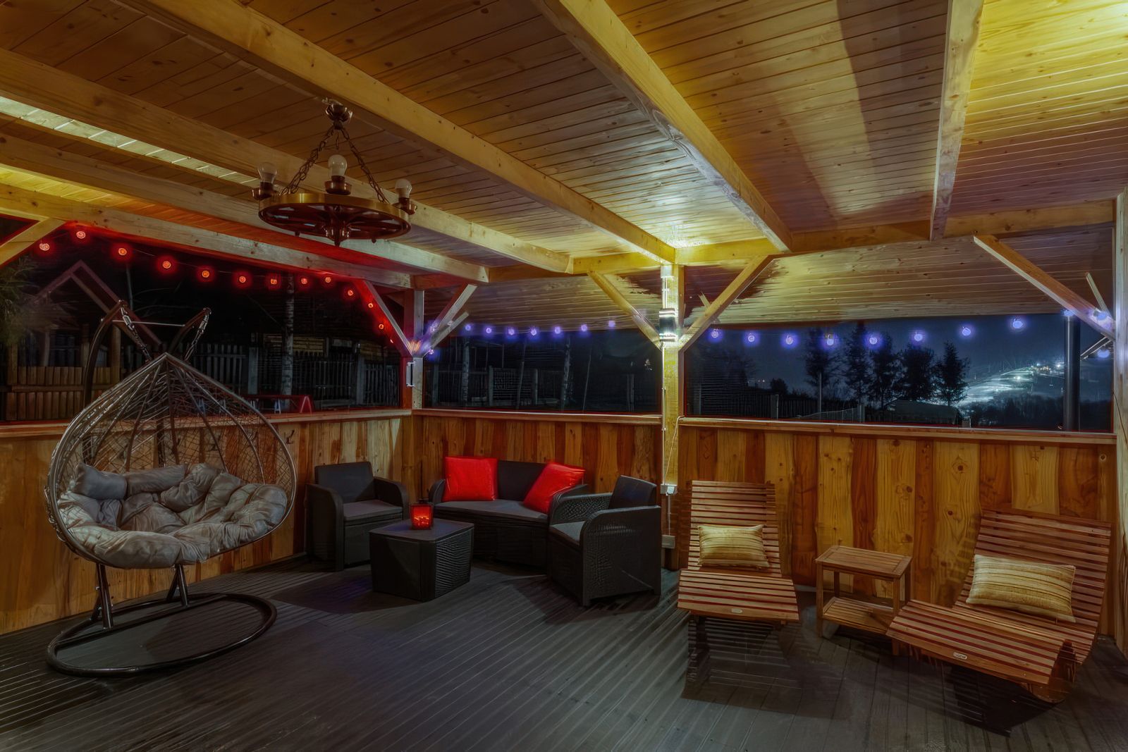 Nocne patio SPA Willa OdNova Tylicz - drewniana huśtawka, leżaki i oświetlenie kolorowe nad Beskidem