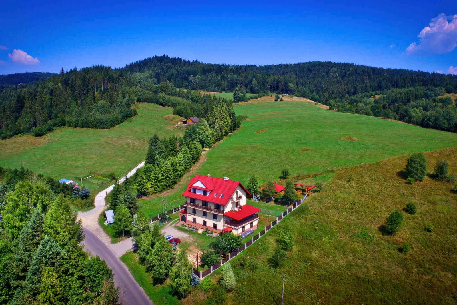 Lot ptaka na Willę OdNovę w Tyliczu - czerwony dach, otoczona zielenią, Beskid Sądecki w tle