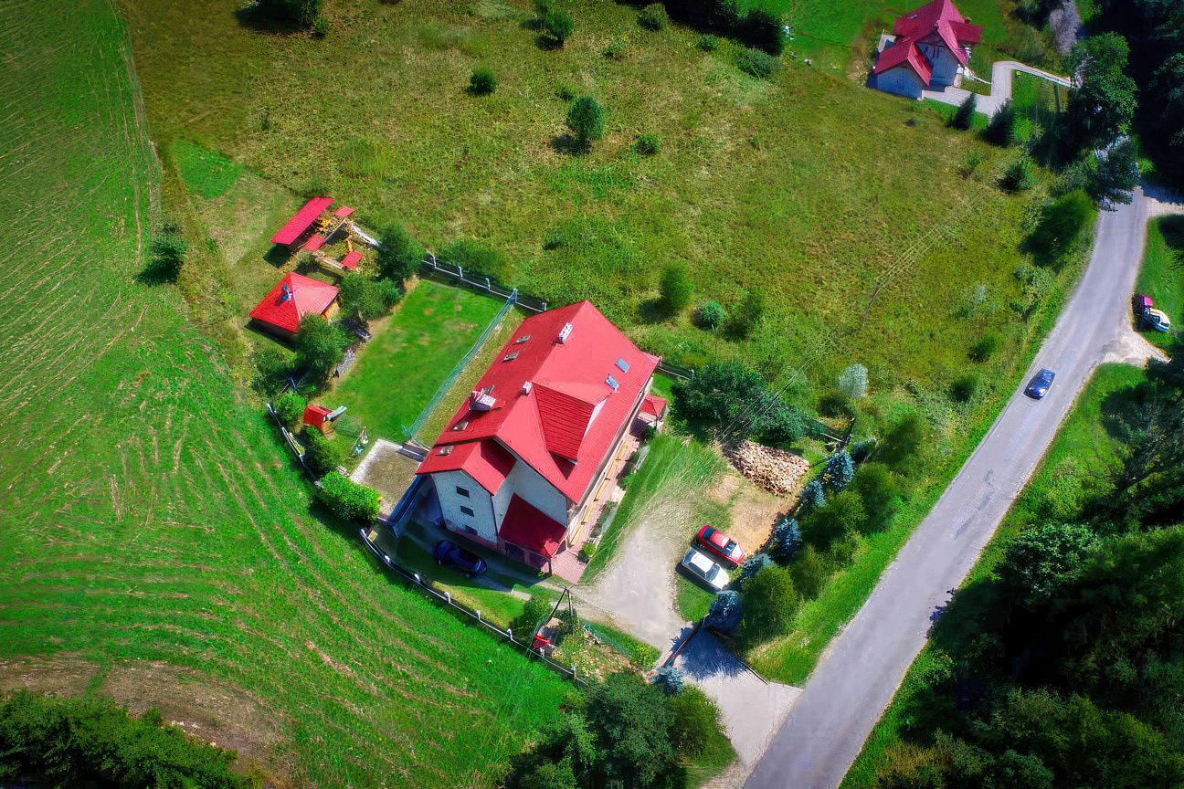 Widok z drona na Willę OdNowę w Tyliczu - czerwony dach, zielone pola, las wokół