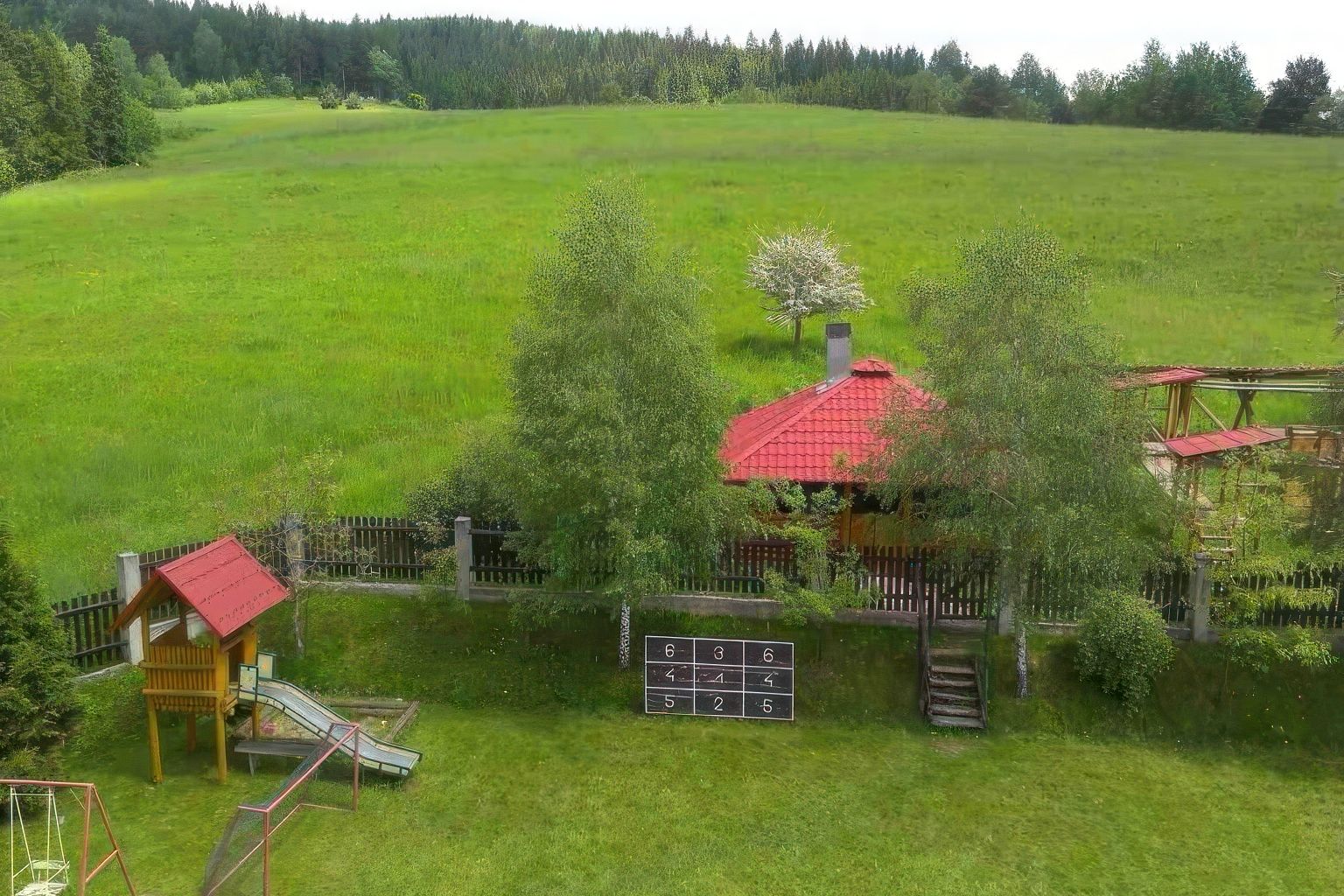 Ogród Willi OdNowa z placem zabaw dla dzieci, huśtawkami, zielonym polem i lasem