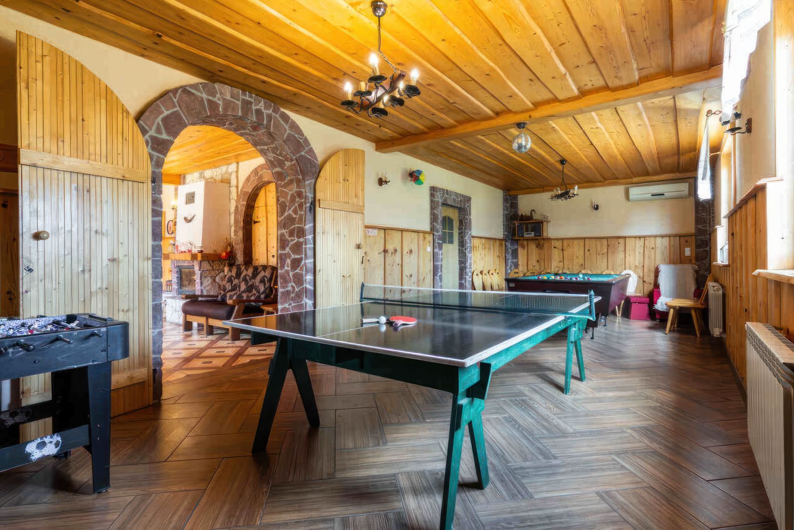 Sala rekreacyjna Willi OdNowa z grami, stołem do ping-ponga, kominkami i drewnianymi elementami